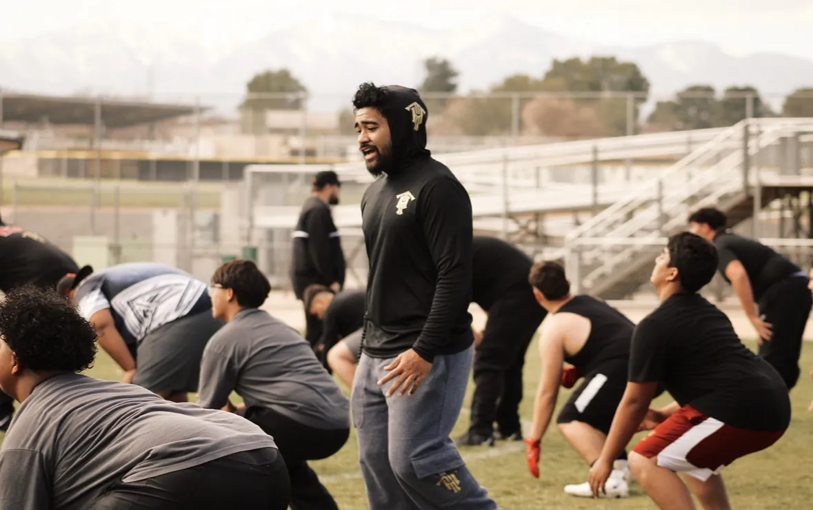 Trench House coach leading a group of linemen through a warm-up on the field